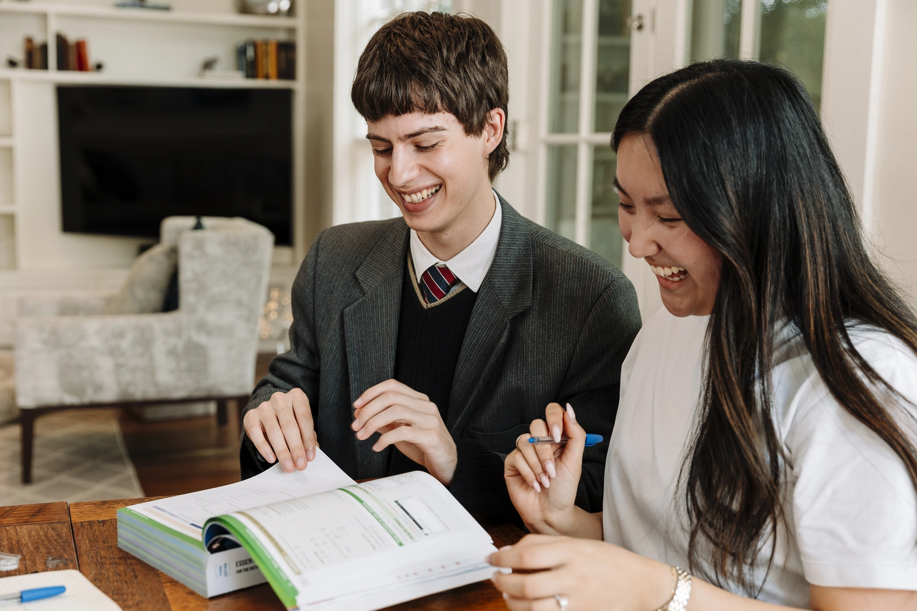 A tutor and student discussing schoolwork at a kitchen table