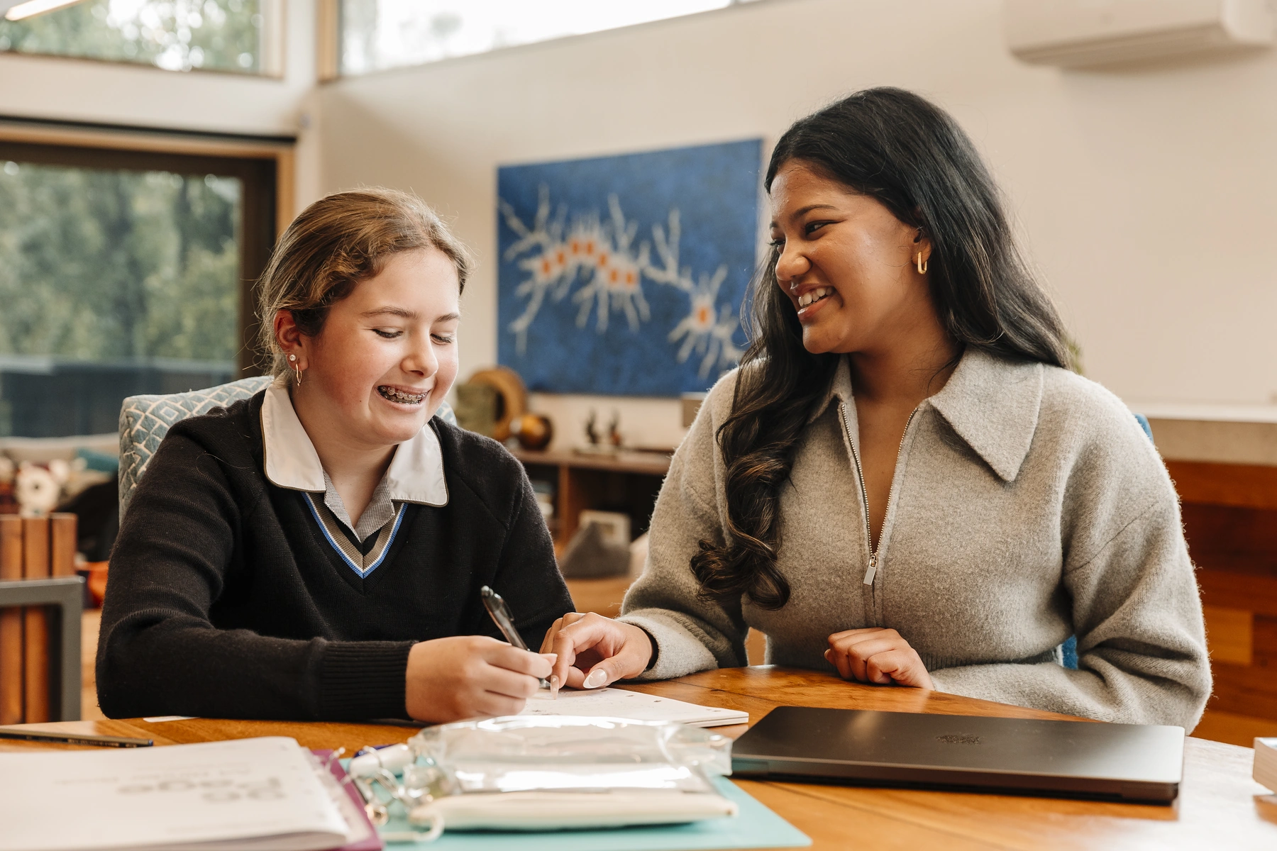 A tutor working beside a secondary student at a table